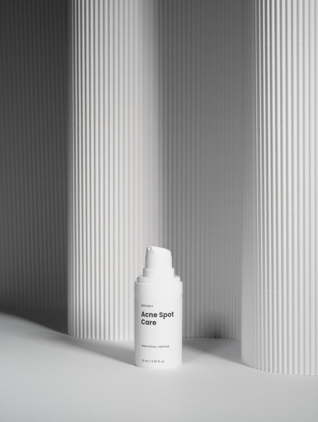 White skincare bottle with pump against a gray striped background