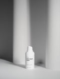 White skincare bottle with pump against a gray striped background