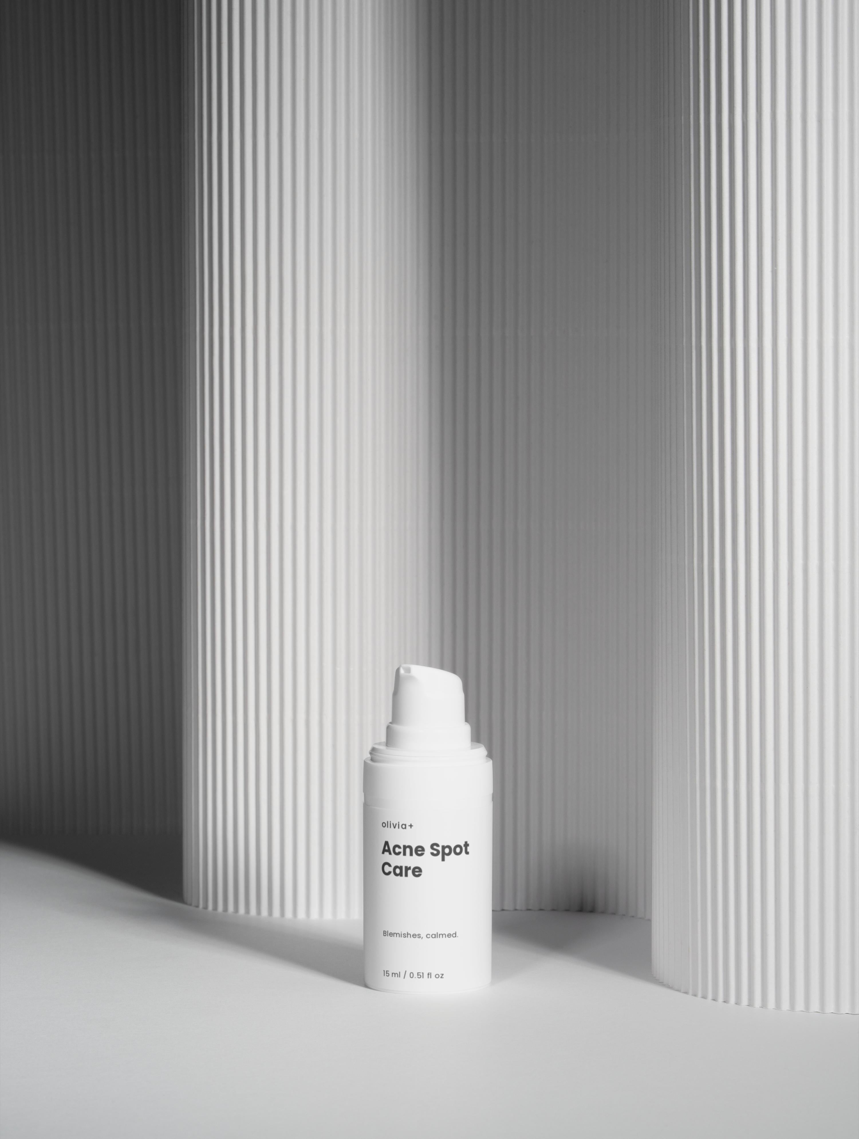 White skincare bottle with pump against a gray striped background