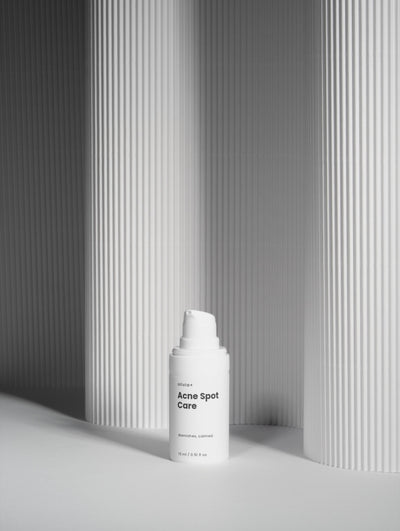 White skincare bottle with pump against a gray striped background