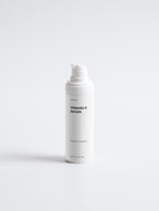 White bottle of Vitamin C Serum on a light gray background