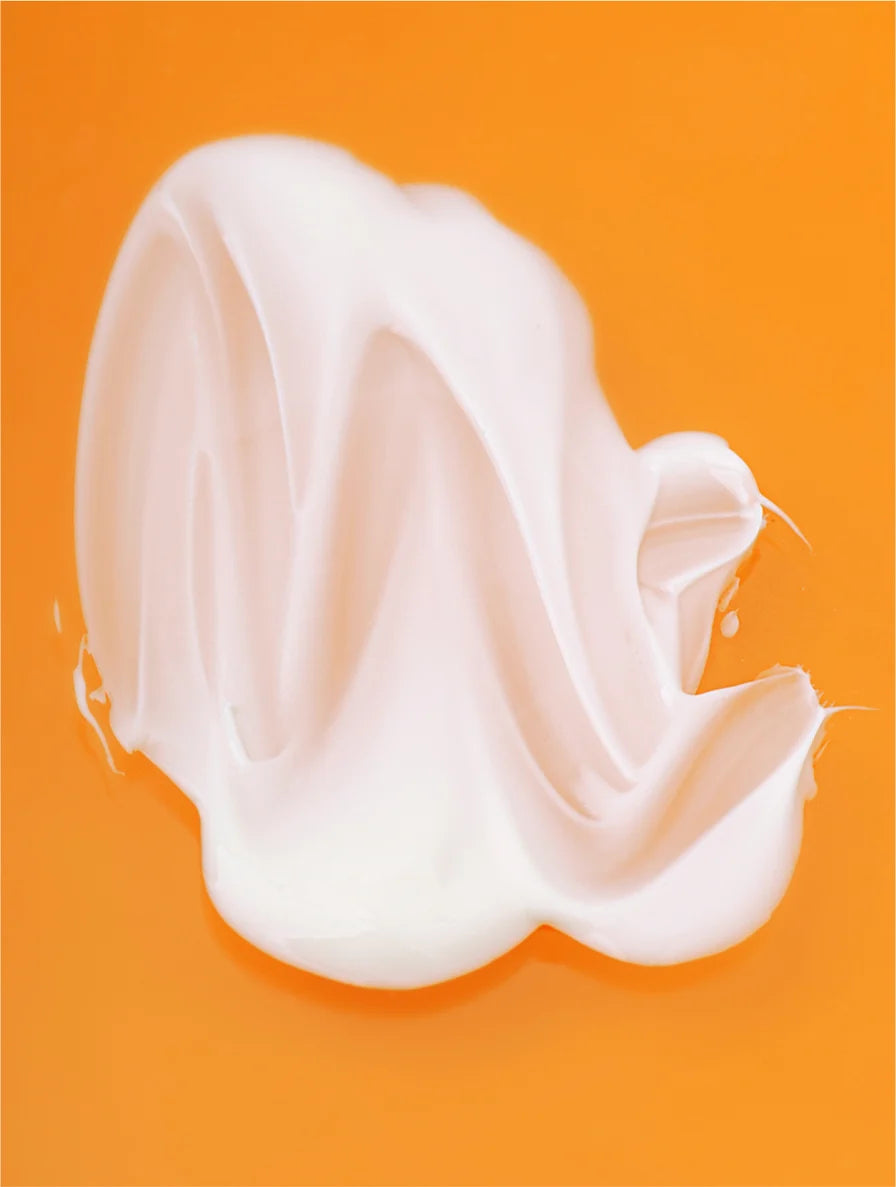 White cream or lotion swatch on an orange background