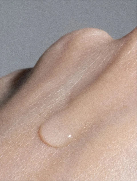 Close-up of a water droplet on skin against a neutral background