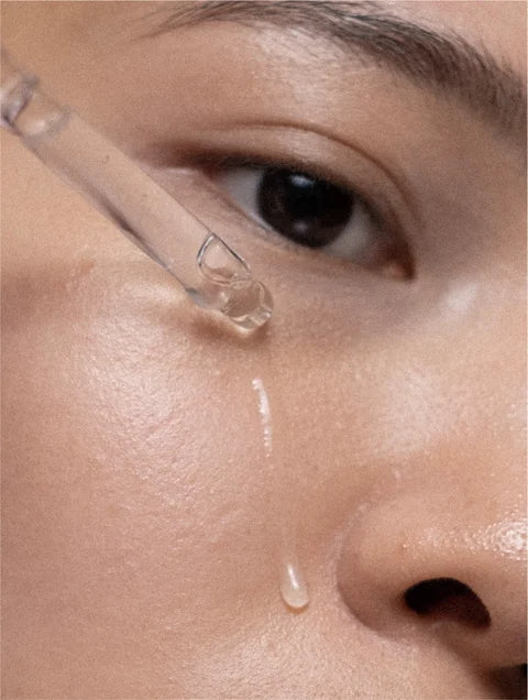 Close-up of a dropper applying liquid to a person's skin