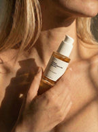 Person holding a skincare bottle labeled 'Ginkgo Antioxidant Gel Booster' against their skin.
