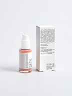 Skincare bottle with pink cap and white label next to its packaging on a light gray background